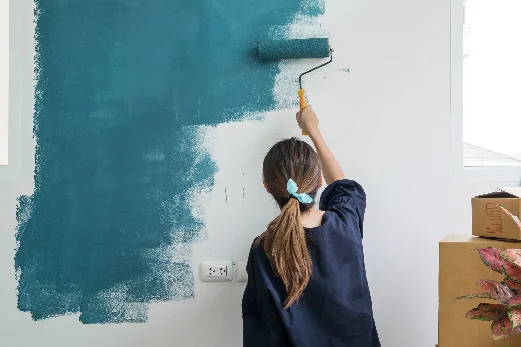 Person streicht Wand mit Farbrolle